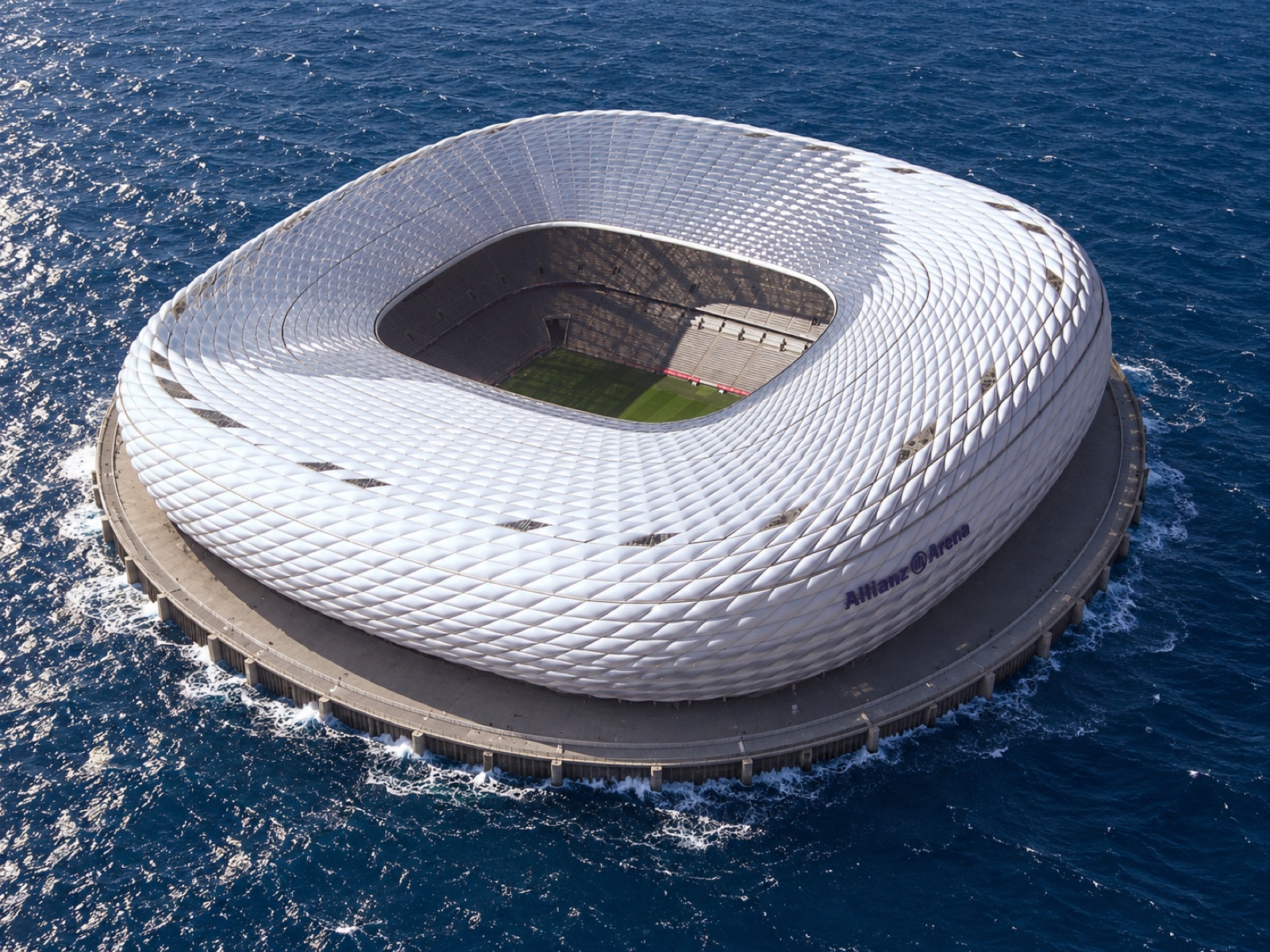 The same stadium seen from above, now standing on a round platform in the middle of the open sea with white waves around it.